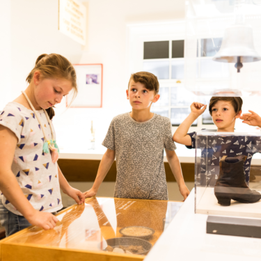 Three young people looking at a museum display