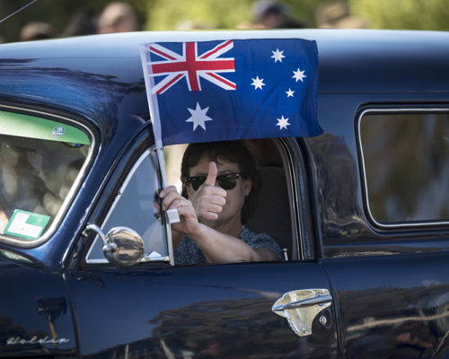 a man holding an Australian flag out of a car window