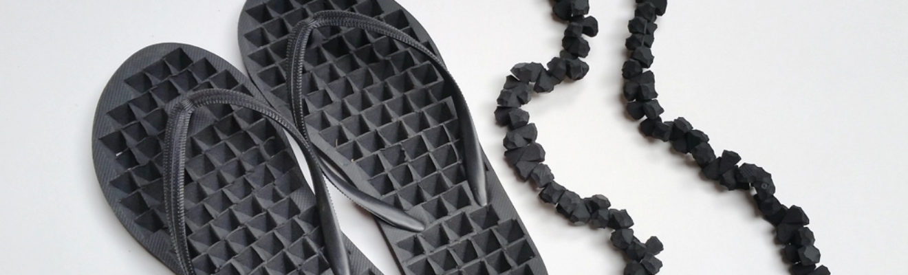 artwork of black thongs and black necklace made from parts of the thongs